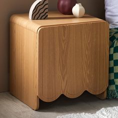 a wooden table with two vases on top of it and a bed in the background