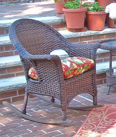 two wicker rocking chairs sitting next to each other on a brick patio with potted plants in the background