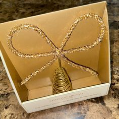 an open box with a gold ribbon on it and some beads in the shape of a bow