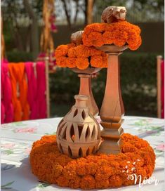 an arrangement of orange flowers and candles on top of a white cloth covered tablecloth