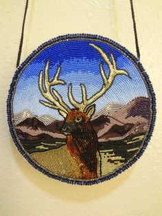 a beaded ornament hanging on a wall with an image of a deer