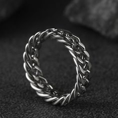 a silver braid ring sitting on top of a black surface