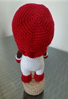 a crocheted red and white ball cap on top of a small cup holder