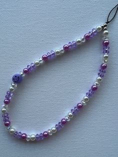 a purple beaded necklace with a smiley face on it