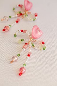 the beaded necklace has pink hearts and green leaves on it, along with other beads