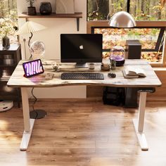 a desk with two computers on it in front of a window