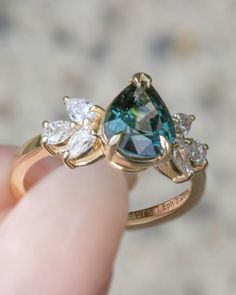 a person is holding a ring with an aqua and white diamond