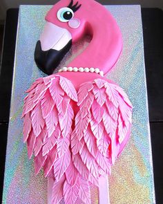 a cake that looks like a pink flamingo with pearls on its head and tail