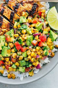 a bowl filled with chicken, corn and avocado on top of white rice