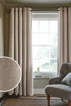 a chair sitting in front of a window next to a white wall with curtains on it