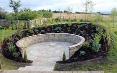 a circular stone bench sitting in the middle of a garden