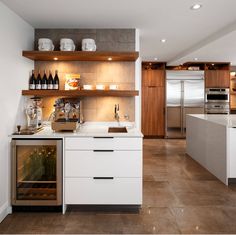 a kitchen with white cabinets and brown tile flooring is pictured in this image, there are wine bottles on the shelves above the sink