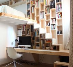 a room with a desk, bookshelf and computer on it in front of a window