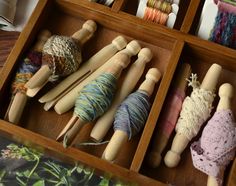 a drawer filled with lots of different types of yarn and wooden pegs in it