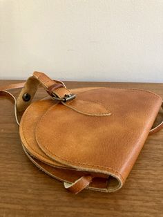 This is an absolutely beautiful handmade leather purse. Featuring a gorgeous minimalist silhouette, the leather has aged wonderfully resulting in a gorgeous patina and charming retro look. As well as the main body, the interior and strap are of the same leather.  This beauty is in excellent condition with only minor signs of wear as pictured. Measurements as follows: 7" across x 6" tall. The bottom is  0.5" wide. The shoulder strap is 0.25" a drop of 23".  Want to see more beautiful vintage bags? Visit the Clothes | Shoes | Bags section of my shop here: https://www.etsy.com/ca/shop/LotusRoadVintage?section_id=27662622 Please visit my shop to see more gorgeous quality vintage items for your modern home: https://www.etsy.com/ca/shop/LotusRoadVintage?ref=seller-platform-mcnav Exciting news! L Handmade Leather Purse, Small Leather Purse, Vintage Leather Handbag, Leather Crossbody Bag Small, Minimalist Silhouette, 70s Boho, Purse Vintage, Boho Accessories, Small Handbags