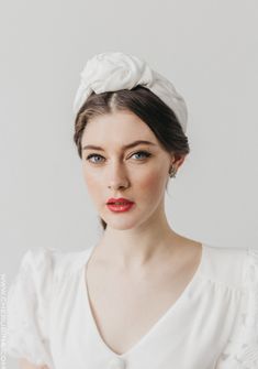 a woman wearing a white dress with a flower in her hair and red lipstick on her lips