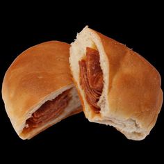 two pieces of bread with meat in it on a black background, cut in half