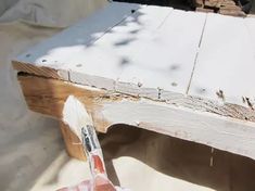 a person is using a brush to paint the top of a wooden table with white paint