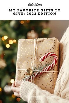 a woman holding a wrapped present in front of a christmas tree with a candy cane