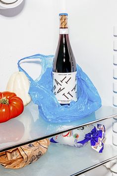 a bottle of wine sitting on top of a glass table next to some vegetables and fruit