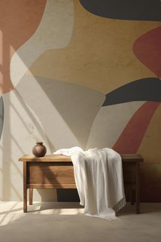 a table with a white blanket on top of it next to a large wall painting