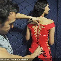 a woman in a red dress standing next to a man with his arm around her