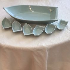 a white table topped with lots of blue bowls and plates on top of a cloth covered table