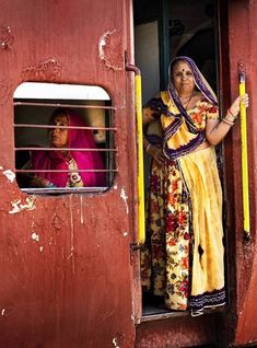 two women are standing in the doorway of a train car, looking out from inside