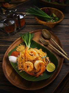 a wooden plate topped with food on top of a table next to utensils