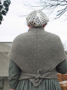 a woman wearing a knitted shawl and holding a wicker basket