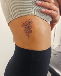 a woman with a flower tattoo on her lower back side ribcage, showing it's thinness