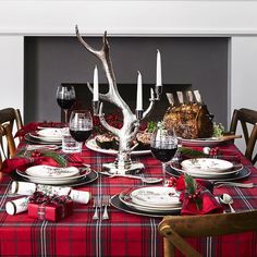 the table is set for christmas dinner with red and black plaid