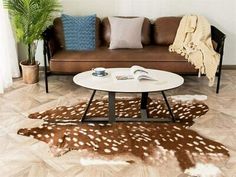 a living room filled with furniture and a deer skin rug on the floor in front of a brown couch