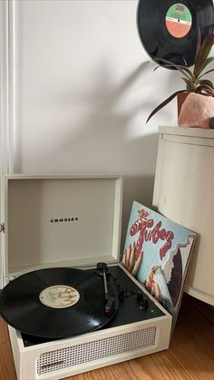 an old record player sitting on top of a wooden floor next to a potted plant