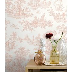 two vases with flowers on a table in front of a wallpapered background