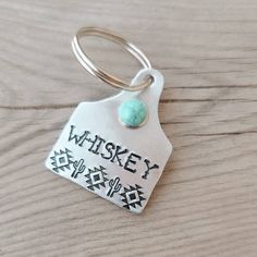 a keychain with a tag that says whiskey and a turquoise bead on it