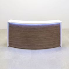 a curved white and wood reception table with blue light at the top in an empty room