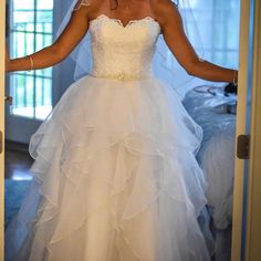 a woman in a wedding dress is standing at the door with her hands out to herself