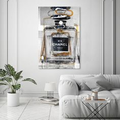 a living room with a white couch and chanel bottle on the wall above it