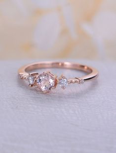 an engagement ring with three stones on it, sitting on top of a white cloth