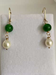 "At an auction last year in Maine, I was able purchase these exquisite pearls. The label on the sleeve indicated that they date back to the 1980s. They boast a stunning creamy white iridescent nacre, radiating elegance. The hand-carved Brazilian emeralds, measuring 12mm, are a recent addition, beautifully complementing the pearls. The lever back is made of 14k gold filled, with a 14k gold stamp, manufactured in the USA. As the birthstone for May, the emerald holds significant meaning. Symbolizing rebirth, it is believed to bestow upon its owner the gifts of foresight, good fortune, and eternal youth. The word \"emerald\" derives from the Greek term \"smaragdus,\" which quite literally translates to \"green,\" reflecting its captivating hue." Classic Jade Jewelry For Wedding, Classic Jade Wedding Jewelry, Elegant 14k Gold Filled May Birthstone Jewelry, Classic Green Pearl Drop Jewelry, Green Pearl Dangle Jewelry, Green Round Classic Pearl Earrings, Green Pearl Jewelry For Gifts, Formal Green Jewelry With High Luster, Formal Green High Luster Jewelry