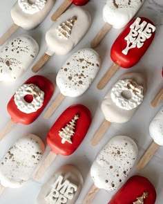 red and white donuts are arranged on wooden skewers with christmas decorations painted on them