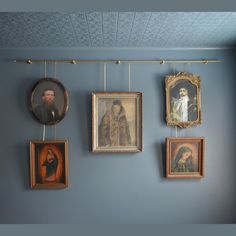 paintings and portraits hang on the wall in an old - fashioned room with blue walls