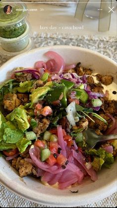 a white bowl filled with salad on top of a table next to a glass jar