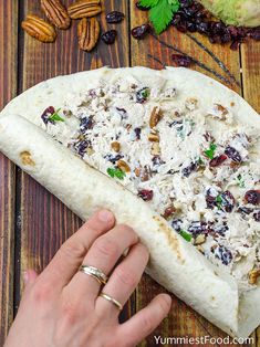 a person holding a tortilla with nuts and other toppings on top of it