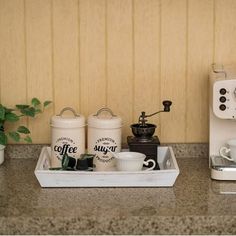 there is a coffee maker and two cups in the trays on the counter next to each other