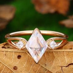 a diamond ring sitting on top of a piece of wood with leaves in the background