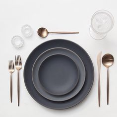 a table setting with silverware and black plates