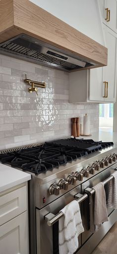 a stove top oven sitting inside of a kitchen next to a counter with towels hanging on it