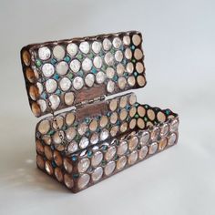 an old wooden box with many circles on the lid and inside, sitting on a white surface